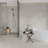 A modern bathroom with light-color concrete look tile featuring a colored body, styled with sleek fixtures.