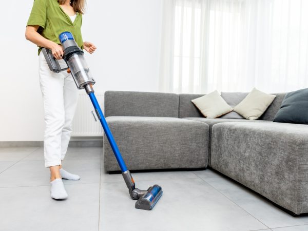 Woman vacuuming living room floor tiles