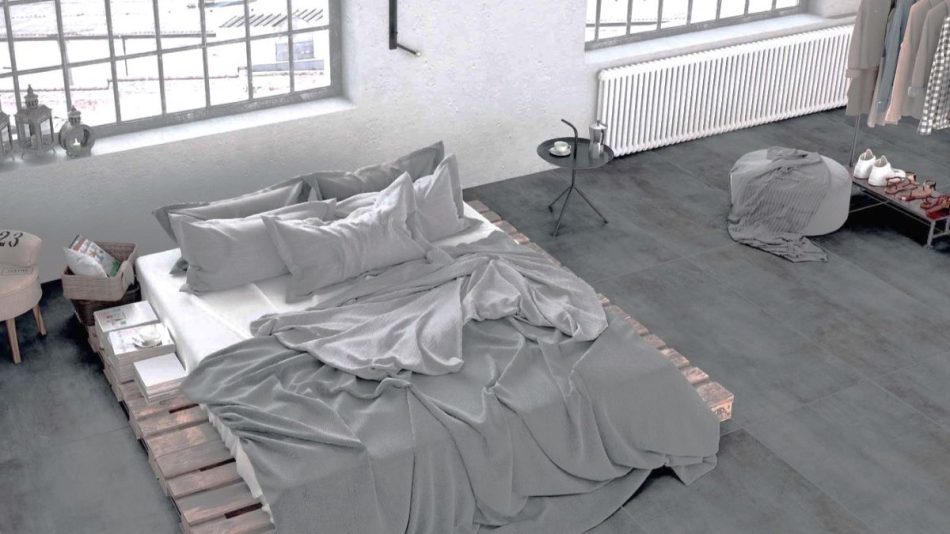 a modern bedroom with grey concrete look tile flooring