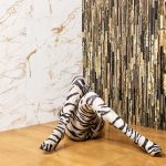 Our Brands 1 Artistic picture of a woman laid down on the floor with her legs crossed in a leopard design legging in front of a two connection wall where each one of the walls has a different Roberto Cavalli tile.