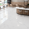 Modern café interior with polished 48x48 Statuarietto porcelain tile flooring and matching Statuarietto tile countertop, featuring subtle grey veining and a glossy white finish.